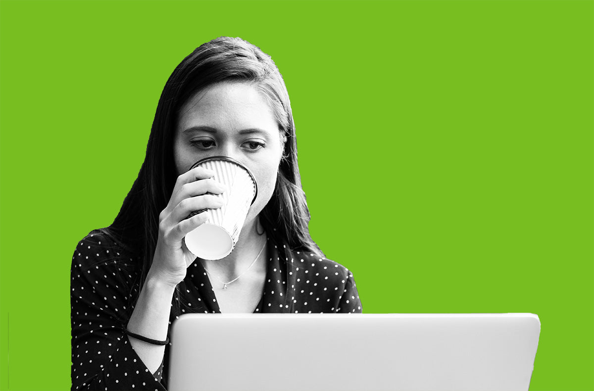 A person drinking coffee in front of a laptop